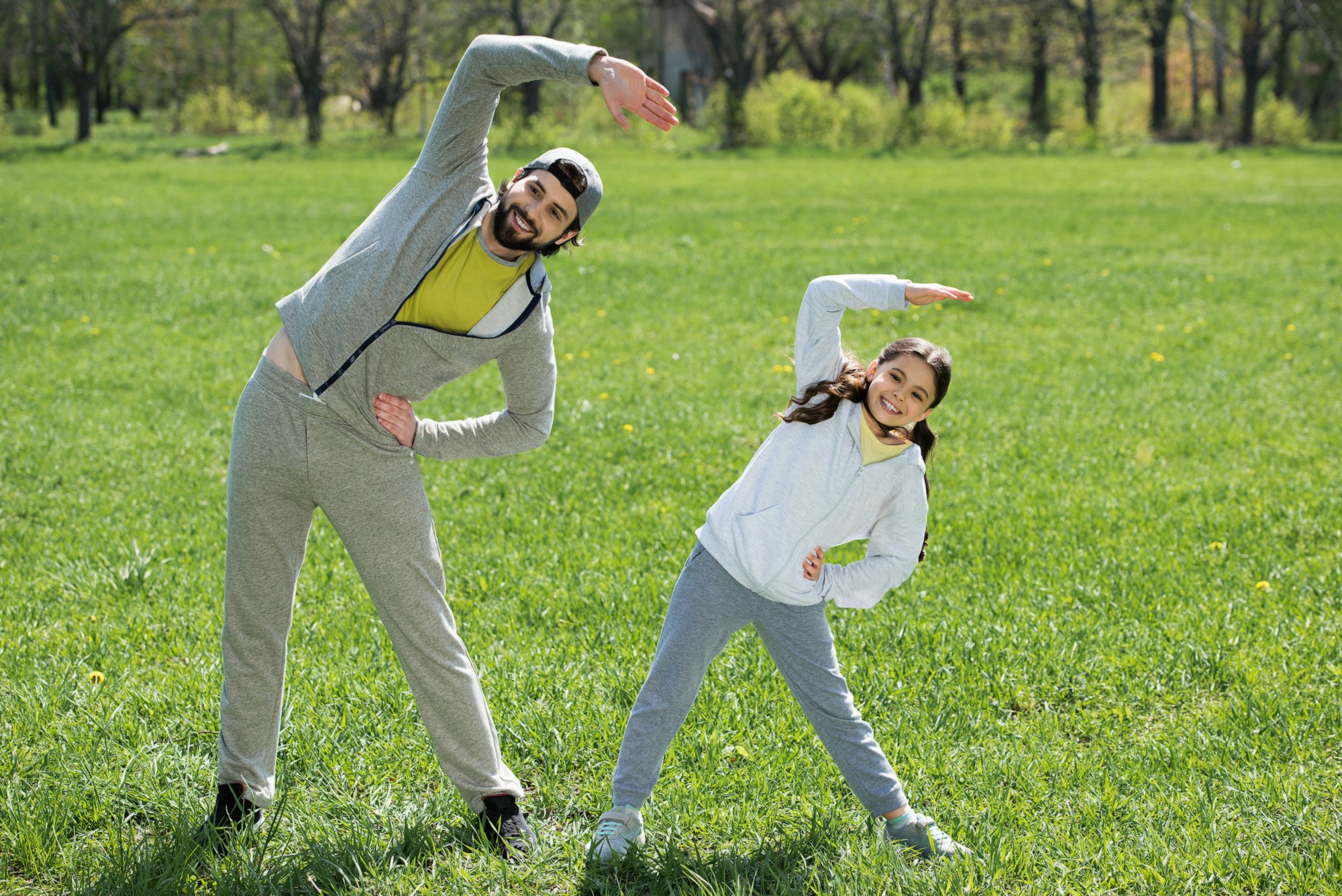 daughter and father doing physical exercise on grass